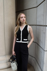 a lady in a black knit vest cardigan with white trim and a pair of black pants